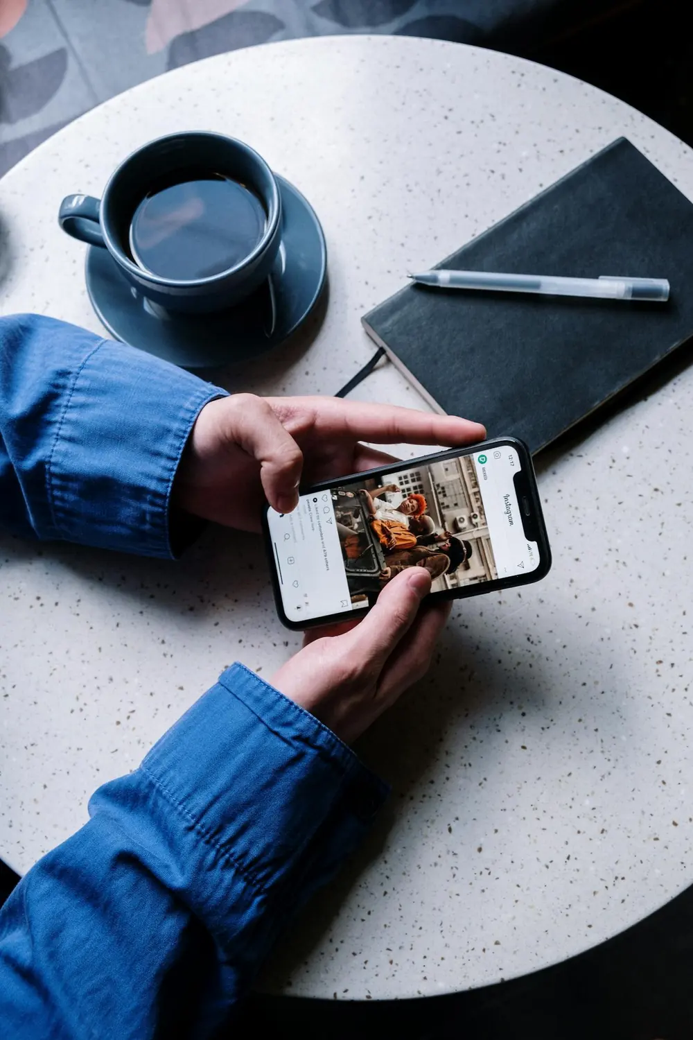 Une personne consulte Instagram sur son smartphone à une table de café