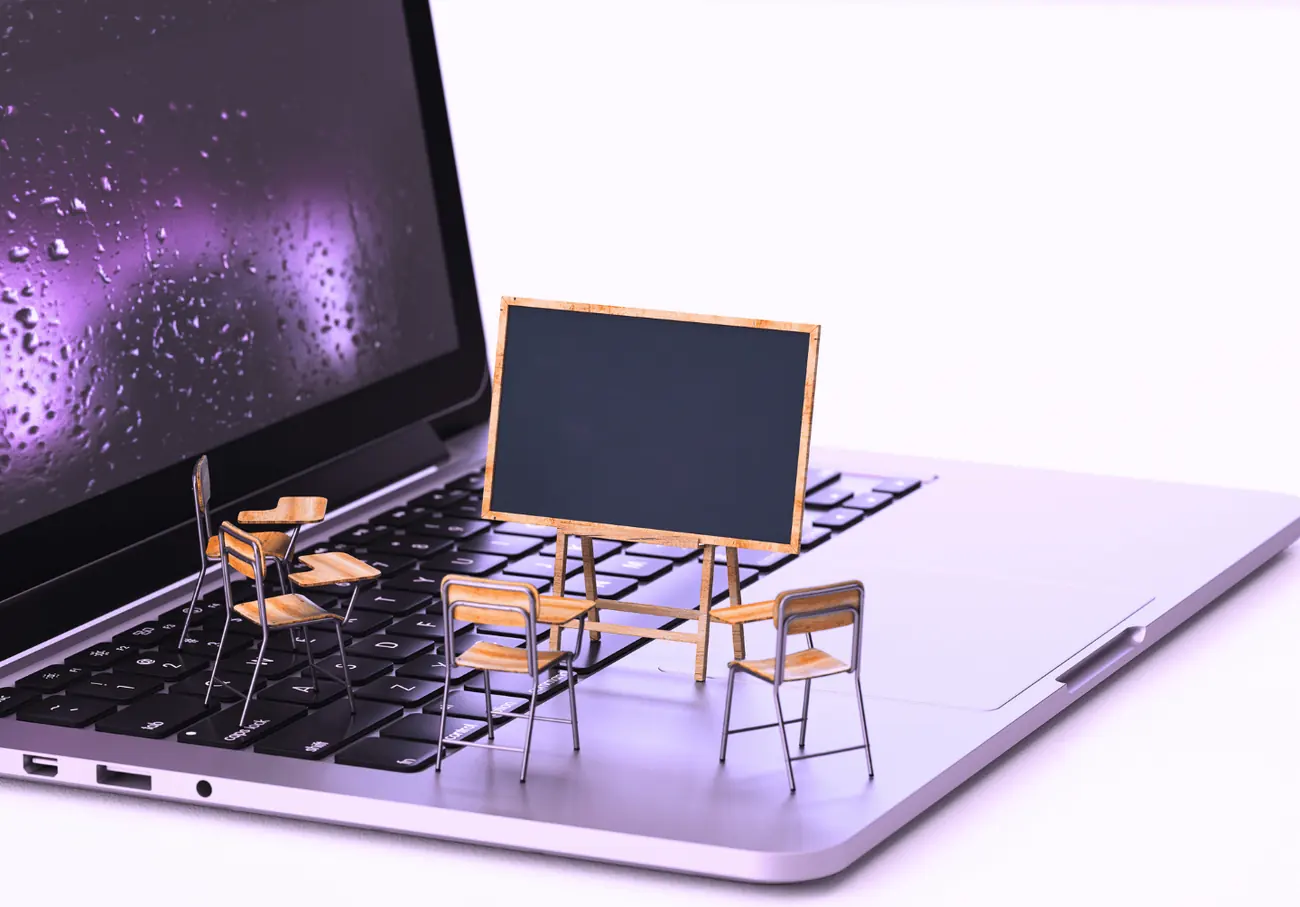 Salle de classe miniature posée sur le clavier d’un ordinateur portable