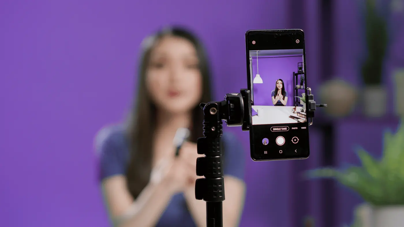 Une créatrice de contenu se filme au smartphone sur fond violet